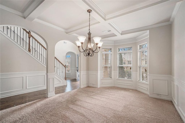 unfurnished dining area with coffered ceiling, dark colored carpet, crown molding, a notable chandelier, and beam ceiling