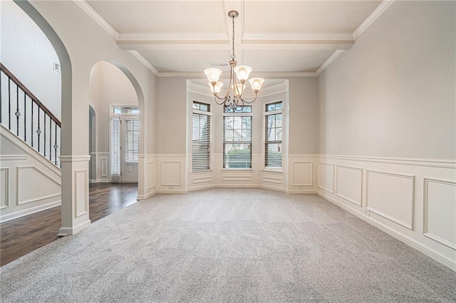 carpeted spare room with beam ceiling, an inviting chandelier, and ornamental molding