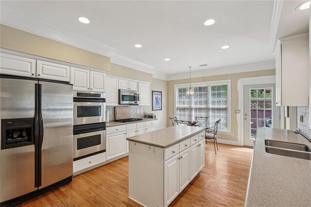 25 Hampreston Ct, Johns Creek, GA 30022 - kitchen with stainless steel appliances, crown molding, white cabinets, a kitchen island, and decorative backsplash