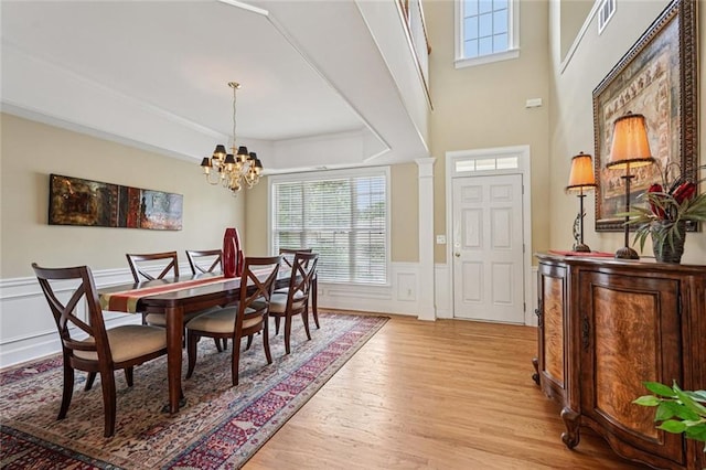 25 Hampreston Ct, Johns Creek, GA 30022 - dining area with light wood finished floors, a chandelier, a wainscoted wall, a decorative wall, and a raised ceiling