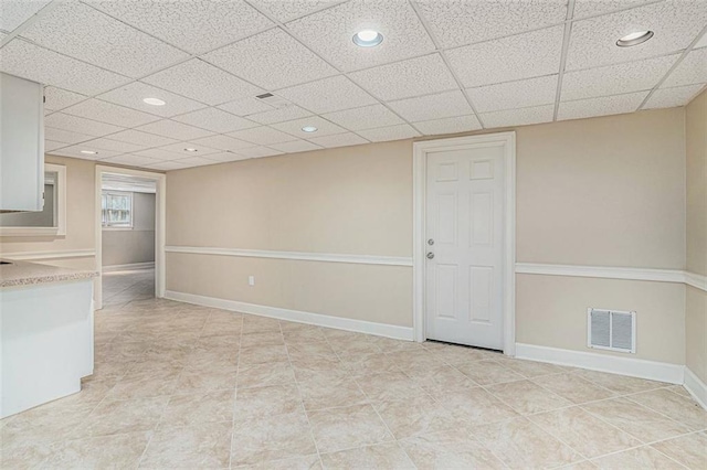 interior space with light tile patterned floors and a drop ceiling