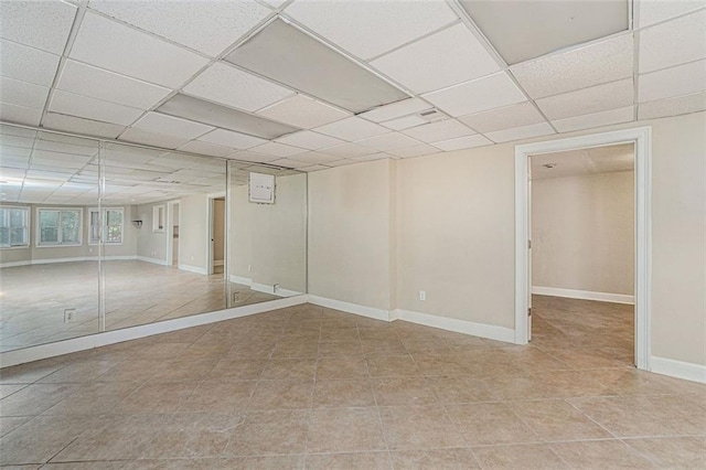 basement with light tile patterned floors and a paneled ceiling