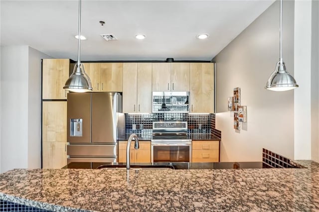 kitchen with appliances with stainless steel finishes, tasteful backsplash, dark stone counters, and light brown cabinetry