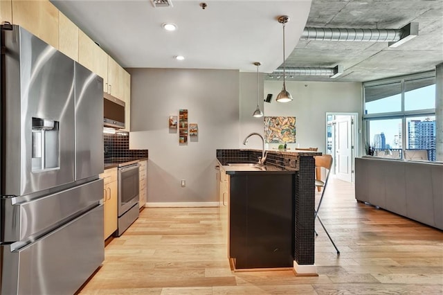 kitchen featuring stainless steel appliances, light wood-style floors, a sink, and light brown cabinetry