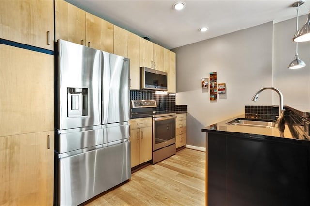 kitchen featuring stainless steel appliances, a sink, light brown cabinetry, tasteful backsplash, and dark countertops