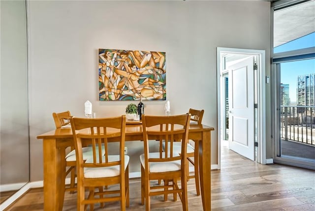 dining space with a view of city, wood finished floors, and baseboards