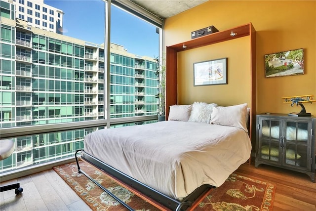 bedroom featuring expansive windows and wood finished floors