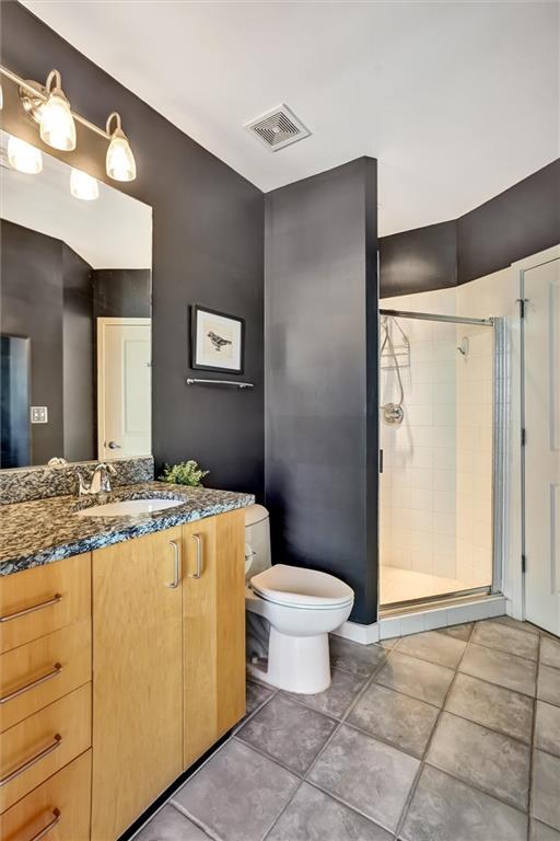 full bath featuring tile patterned flooring, toilet, vanity, visible vents, and a shower stall