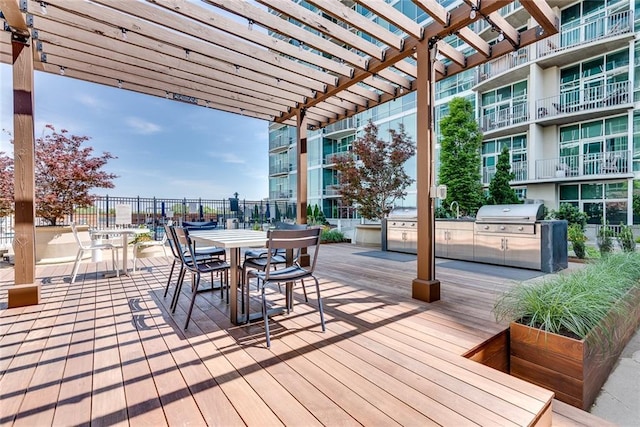 wooden terrace with an outdoor kitchen, a grill, and a pergola