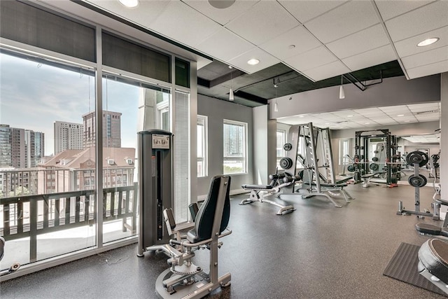 workout area with a paneled ceiling and a city view