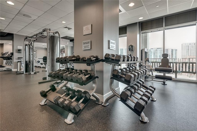 workout area with a wall of windows, a paneled ceiling, and baseboards