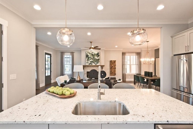 kitchen featuring decorative light fixtures, a kitchen island with sink, and high end fridge