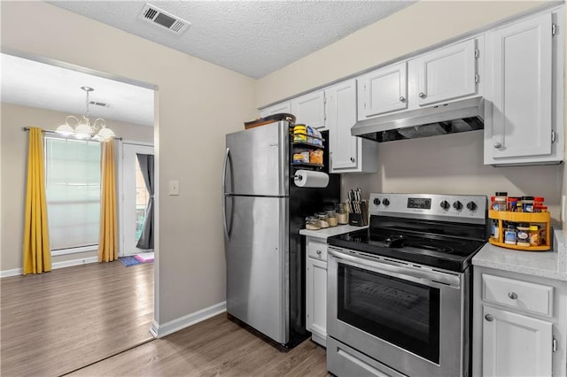kitchen with under cabinet range hood, light countertops, visible vents, light wood-type flooring, and appliances with stainless steel finishes
