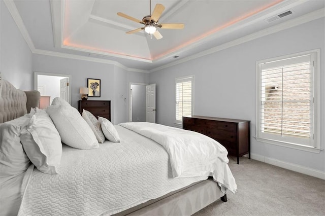 carpeted bedroom with ceiling fan, ornamental molding, and a raised ceiling