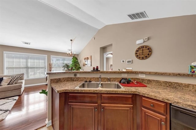 kitchen with a sink, visible vents, light wood-style floors, and vaulted ceiling