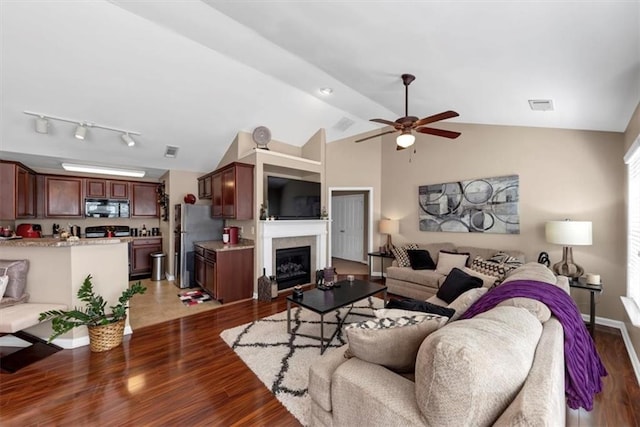 living room with a glass covered fireplace, visible vents, lofted ceiling, and wood finished floors