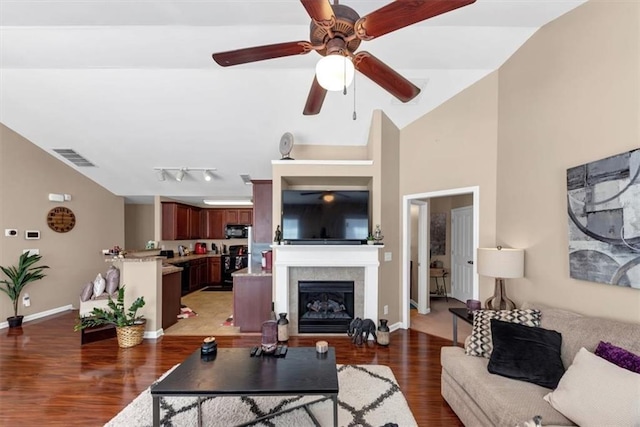 living area with a glass covered fireplace, visible vents, light wood-style floors, and lofted ceiling