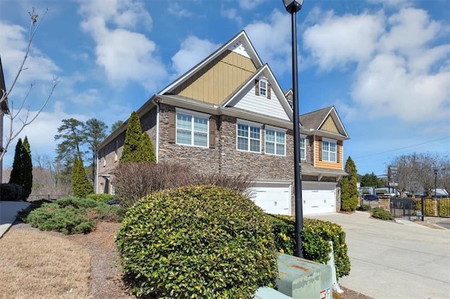 craftsman-style home with board and batten siding, an attached garage, stone siding, and driveway