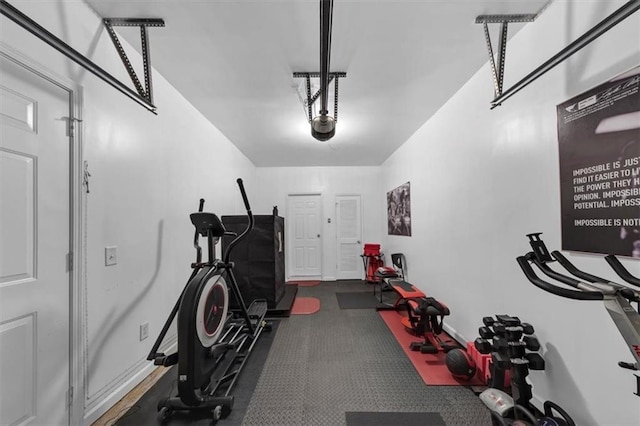 exercise room with a garage and baseboards