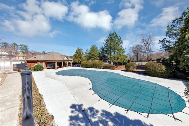 view of swimming pool featuring a covered pool, a patio area, and fence