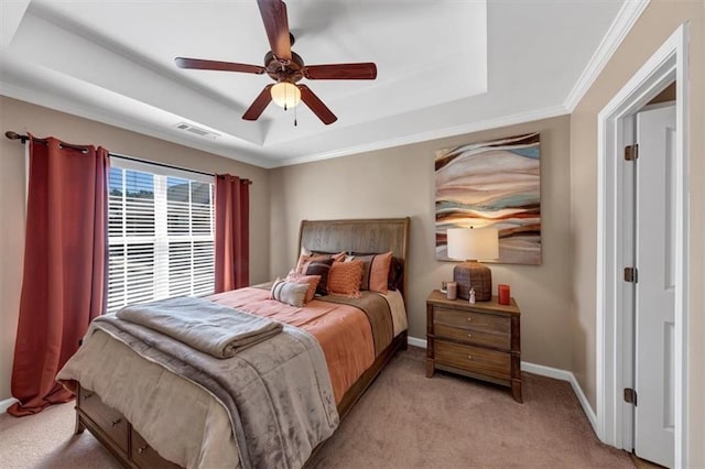 bedroom with visible vents, crown molding, baseboards, light colored carpet, and a raised ceiling