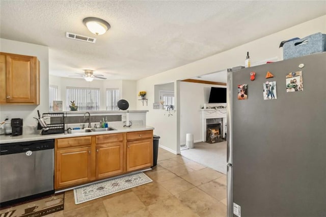 kitchen featuring visible vents, a ceiling fan, a sink, appliances with stainless steel finishes, and a peninsula