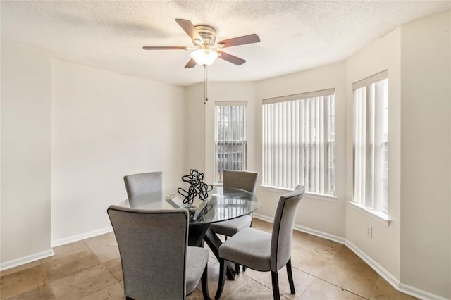 dining area featuring baseboards, a textured ceiling, and a ceiling fan