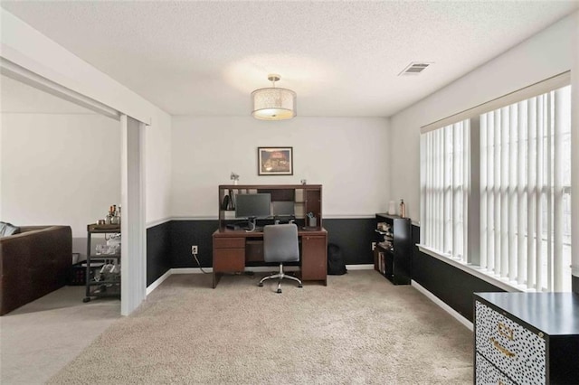 carpeted office space featuring visible vents, baseboards, and a textured ceiling