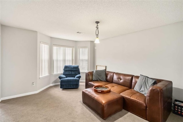 living area featuring carpet flooring, baseboards, visible vents, and a textured ceiling