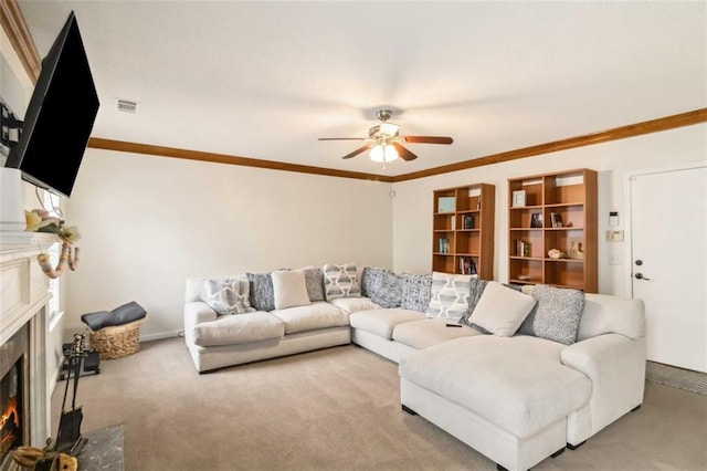 carpeted living area with visible vents, ceiling fan, crown molding, and a lit fireplace