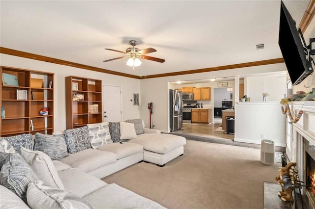 living area with visible vents, a fireplace with flush hearth, light colored carpet, ornamental molding, and a ceiling fan