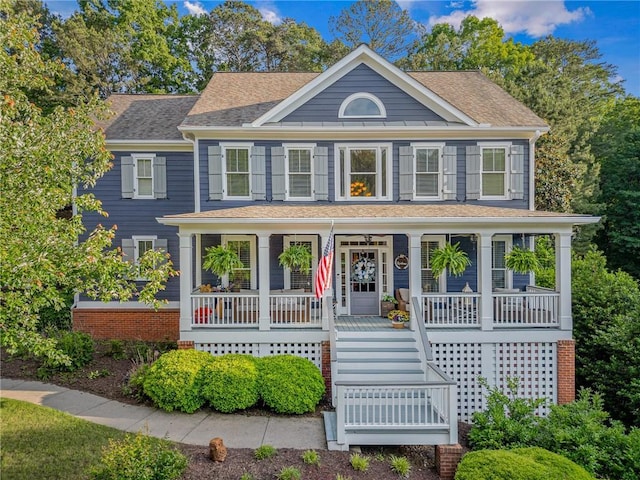 view of front of property featuring a porch, stairway, and a shingled roof