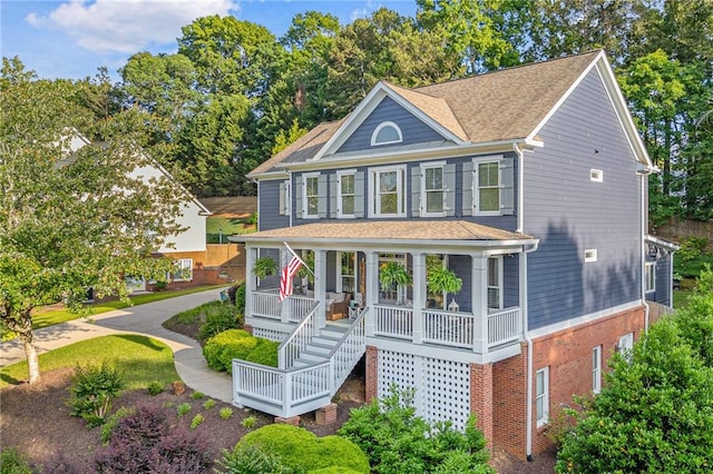 view of front of house featuring a porch, brick siding, and roof with shingles