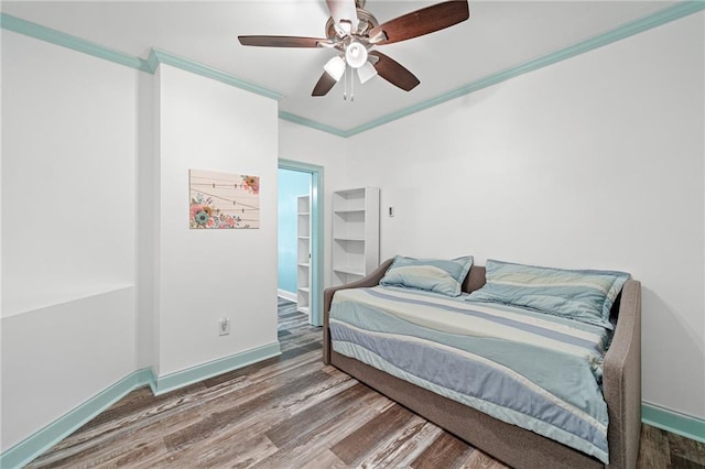 bedroom featuring wood finished floors, crown molding, baseboards, and ceiling fan