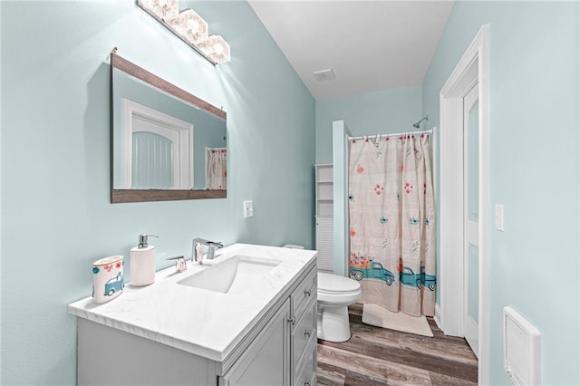bathroom featuring wood finished floors, a shower with shower curtain, toilet, and vanity