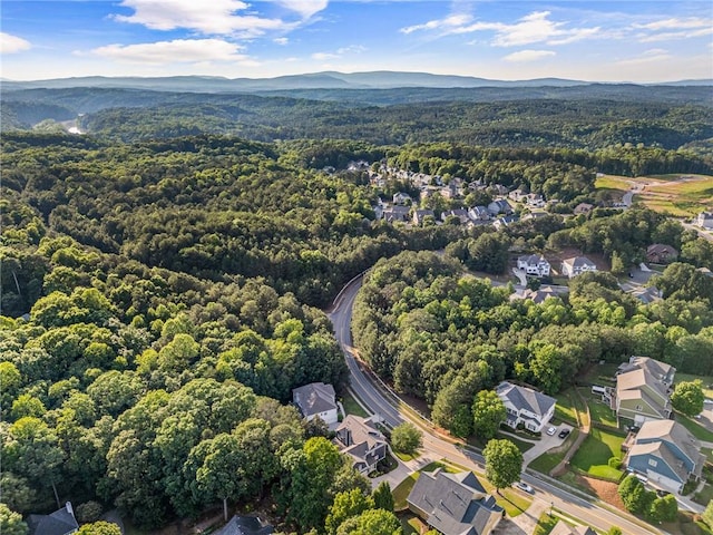 aerial view of property's location with a heavily wooded area, nearby suburban area, and mountains