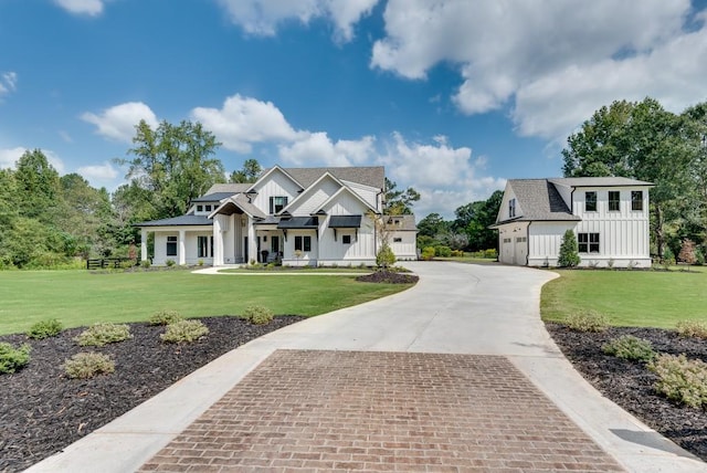 modern farmhouse with a garage, driveway, a front lawn, and board and batten siding