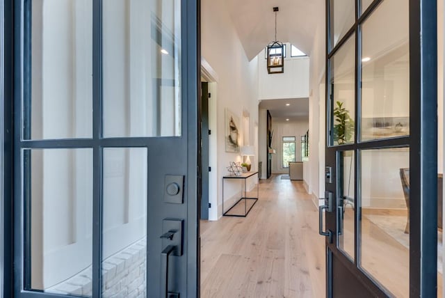 foyer entrance with a towering ceiling, light wood-style flooring, and baseboards