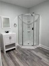 bathroom with hardwood / wood-style flooring, walk in shower, and vanity