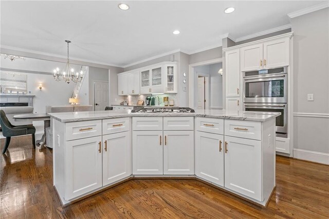 775 Barberry Dr, Milton, GA 30004 - kitchen with stainless steel appliances, white cabinets, dark wood-style floors, ornamental molding, and a chandelier