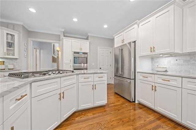 775 Barberry Dr, Milton, GA 30004 - kitchen featuring appliances with stainless steel finishes, ornamental molding, white cabinets, tasteful backsplash, and light wood-style flooring