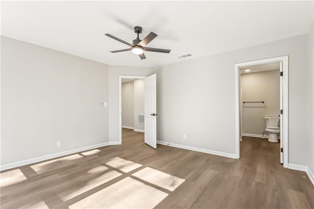 unfurnished bedroom with ensuite bath, ceiling fan, and wood-type flooring