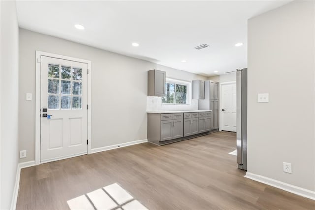 kitchen featuring tasteful backsplash, light hardwood / wood-style flooring, stainless steel refrigerator, and gray cabinetry