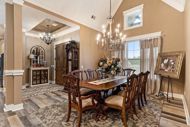 dining area with lofted ceiling, a tray ceiling, an inviting chandelier, crown molding, and hardwood / wood-style floors