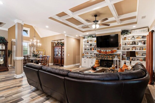 living room featuring beamed ceiling, light hardwood / wood-style flooring, coffered ceiling, a fireplace, and ceiling fan with notable chandelier