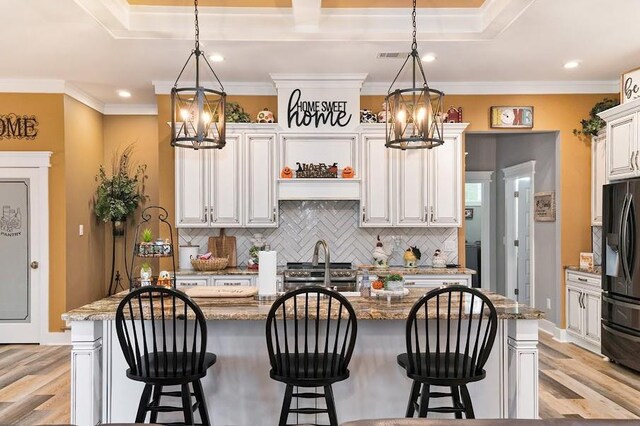 kitchen with white cabinets, stone countertops, and a kitchen island with sink