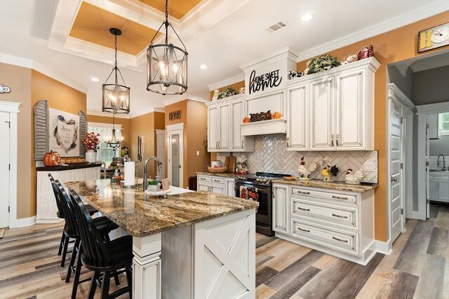 kitchen featuring an island with sink, white cabinetry, stainless steel electric stove, and dark stone counters