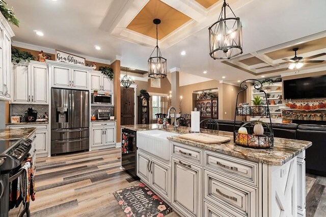 kitchen with light hardwood / wood-style floors, sink, stainless steel appliances, a center island with sink, and decorative light fixtures