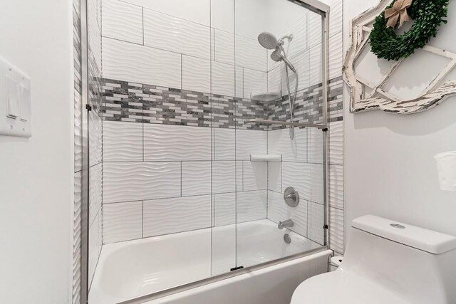 bathroom with bath / shower combo with glass door and toilet