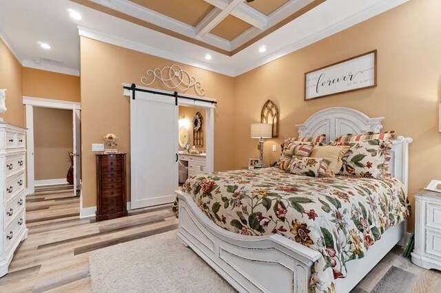 bedroom with light wood-type flooring, coffered ceiling, a barn door, ensuite bath, and crown molding